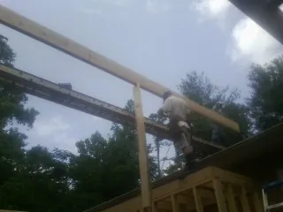 Carpenter setting a ridge beam over a new addition frame — Ice Dam Removal by Roofing Brothers in Cedar