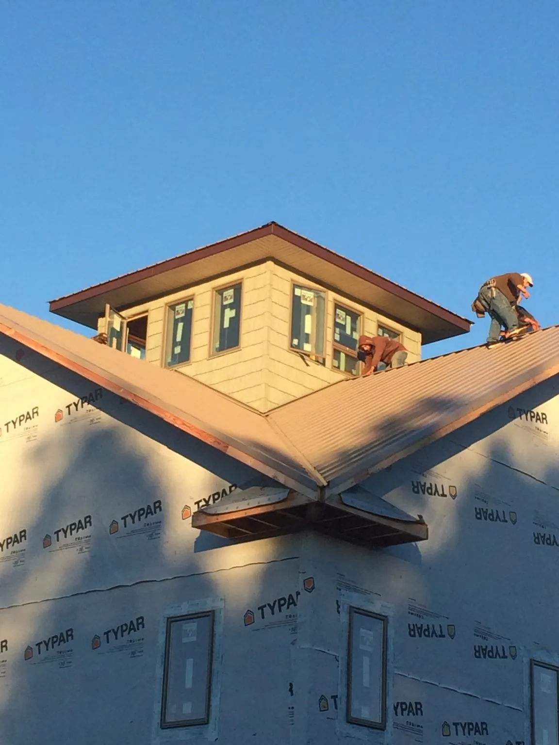 Roofers working around a rooftop cupola on a new metal roof at sunset — Roof Waterproofing in Cedar by Roofing Brothers